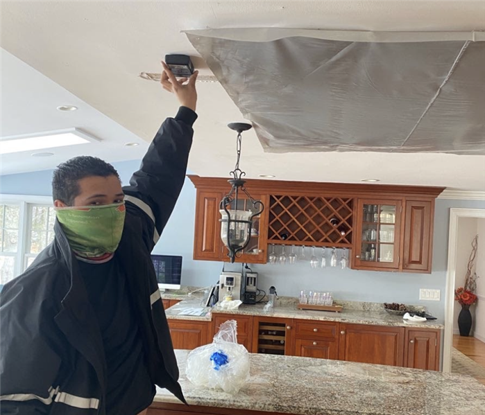 man holding a device to a ceiling